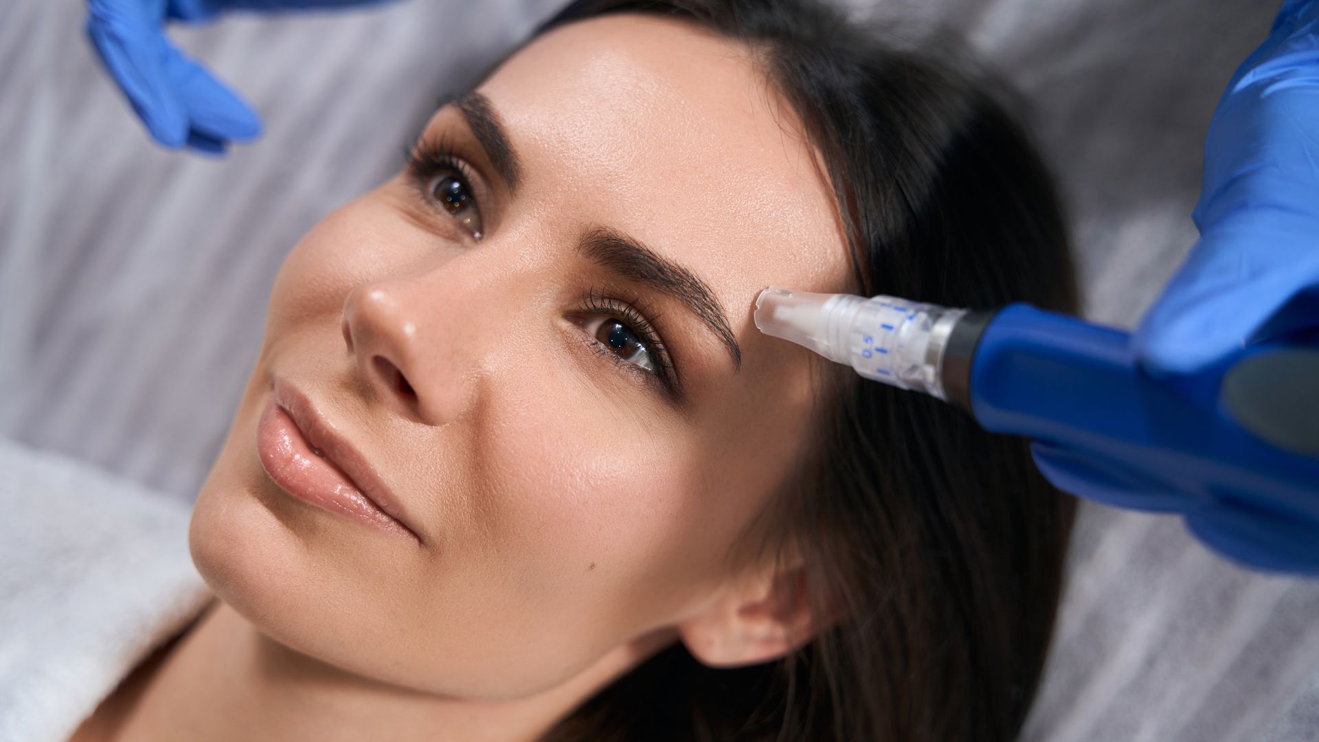 Woman holding device microneedle mesotherapy, doing skin resurfacing procedure